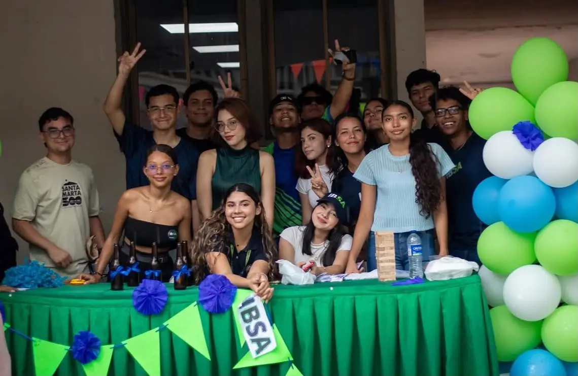 Estudiantes posan en el stand de IBSA, decorado con globos verdes y blancos.