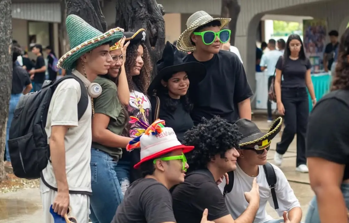 Estudiantes con sombreros, pelucas y gafas de colores posan durante un juego.